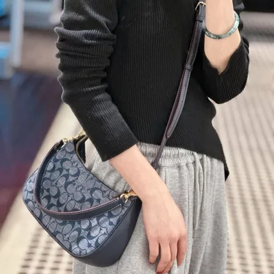 A patterned crescent shoulder bag worn with a black top