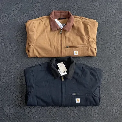 A tan work jacket with a brown collar folded above a navy zip jacket